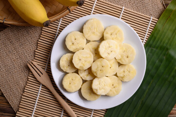 Sliced banana fruit on white dish with fork ready to eating, Tropical fruit