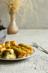 Traditional turkish various pistachio baklava and burma kadayif in plate on white rustic table, holiday dessert concept
