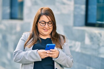 Fototapeta premium Young plus size businesswoman smiling happy using smartphone at the city.