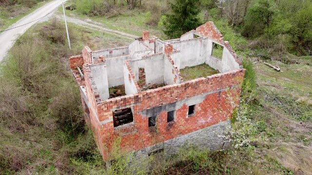 Aerial drone view of house destroyed and burned in war by artillery. Ruined and damaged home in village as war aftermath. Abandoned buildings. House in ruins.