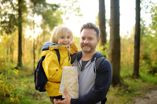 Schoolchild And Mature Father Hiking Together And Exploring Nature. Boy With Dad Spend Quality Family Time Together In Sunny Forest. Adventure, Scouting, Orienteering And Hiking Tourism For Kids.