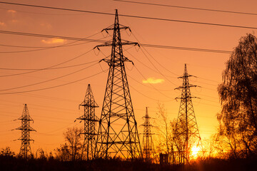 Electric powerlines. High voltage power lines, pylons over sunset orange red sky with sun