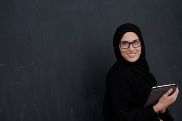 Young Arab businesswoman in traditional clothes or abaya holding tablet computer