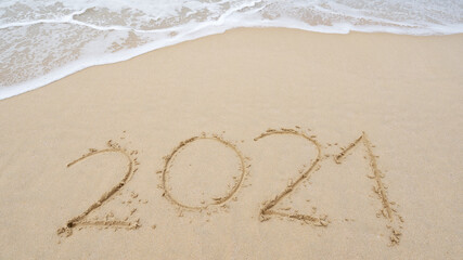 Happy New Year 2021 Text on the beach, 2021 year message hand written in sand on beautiful beach Waves crashing on sandy shore background. New Years concept