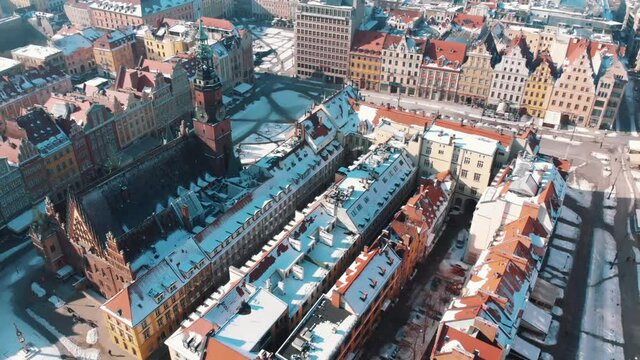 Aerial footage of Wroclaw Market Square with Town Hall. Bright sunny day in the city of Wroclaw, Poland. Colorful old buildings. Streets covered with snow. Winter season.