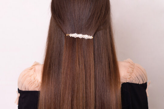 Female back with long straight brunette hair with clip in hairdressing salon