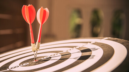 bullseye target or dart board has red dart arrow throw hitting the center of a shooting for...