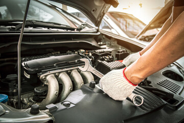 Car care maintenance and servicing, Close-up hands of auto mechanic are using the wrench to repairing car engine problems at auto repair garage. Concepts of check and services insurance.