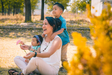 Mamá mexicana con sus hijos jugando en un parque felices 