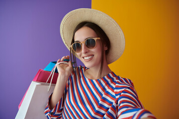 Young woman with shopping bags on colorful background