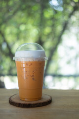 Iced Thai milk tea in takeaway glass on table