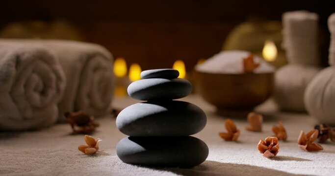 Beautiful composition of various spa bodycare supplements. Close up shot of massage hot stones with bath salt, towels and candles on background 4k footage