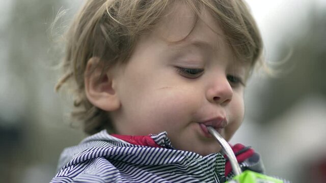 Child drinking juice with straw, little boyd drink snack