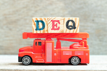 Fire ladder truck hold letter block in word DEQ (Abbreviation of Delivered Ex Quay) on wood...
