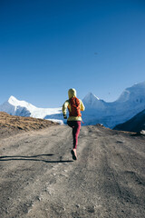 Woman trail runner cross country running in high altitude winter nature.