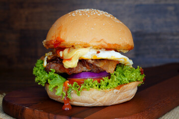 Pork Burger and Bacon close up on a wooden cutting board , Tomatoes, lettuce, home made.