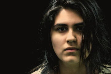 Latina teen in front of black background looking at camera