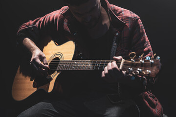 Male guitarist playing acoustic guitar close up.