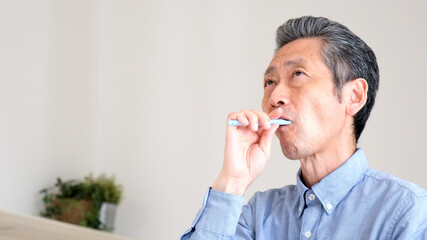 笑顔で歯をブラシで磨くシニア男性