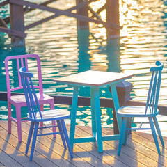 Colorful cute vintage table and chairs on the terrace or restaurant. near the water of lake at time of sunset or evening time.