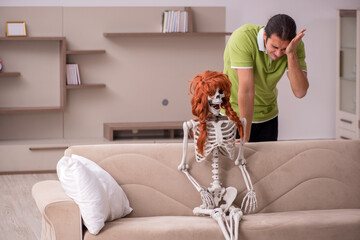 Young man sitting on the sofa with female skeleton