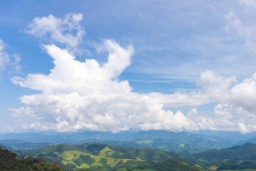 Fototapeta premium White big clouds and blue sky over the mountain hill valley of the village of Thailand, Asia.