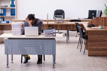 Fototapeta premium Young male employee unhappy with excessive work in the office