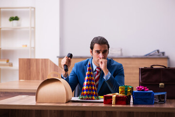 Young male employee celebrating Christmas at workplace