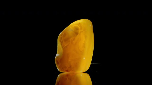 Thin amber stone with transparent yellow matt and red elements reflects bright electric light extra macro