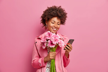 Glad Afro American lady in stylish clothes checks messages online gets congratulations on birthday...