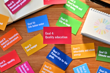 There is a card with the statement Goal 4:Quality education on table one of the goals of the SDGs and a symbol.