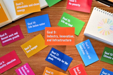 There is a card with the statement Goal 9:Industry, Innovation, and Infrastructure on table one of the goals of the SDGs and a symbol.