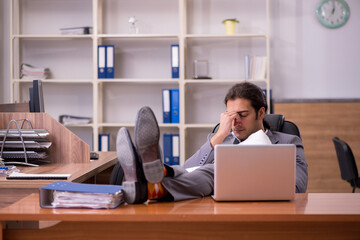 Young male employee sleeping at workplace