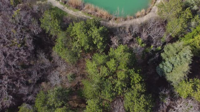 Top view of the spring forest and a beautiful small blue lake in the mountains. Stock footage. Drone flight over a mountain forest, stunning views. Crimean beauty peninsula.
