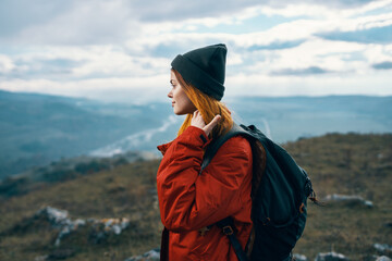 woman travels in the mountains landscape backpack red jacket and hat model