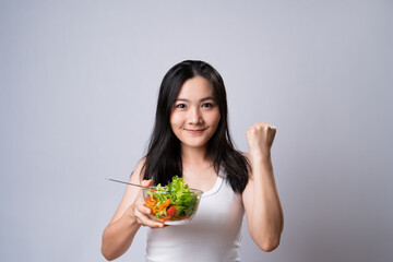 Asian woman eating salad isolated over white background.