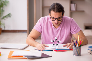 Young male student physicist preparing for exam at home