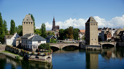 Fototapeta na wymiar Wehrtürme auf der mittelalterlichen Brücke über die Ill mit bedeckter Brücke, ponts couvert, im Viertel von Straßburg petite France, blauer Himmel mit Wolken