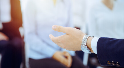 Fototapeta premium Business man making presentation to group of people in office. Speaker delivering a seminar to his colleagues. Teamwork and coaching concept