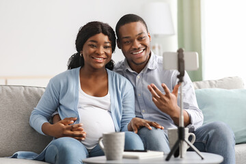 Cheerful black bloggers broadcasting from home, pregnancy blog concept