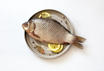 Raw uncooked crucian carp with peppers and lemon on white background