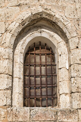 Fototapeta na wymiar Ventana en arco apuntado de estilo románico siglo XII con barrotes de hierro en la iglesia Santiago apóstol de Villalba de los Alcores, provincia de Valladolid, España