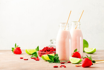 Healthy blended diet smoothie drink with strawberry and goji berries, chia seeds and lime. Glass bottles with eco fendley straws