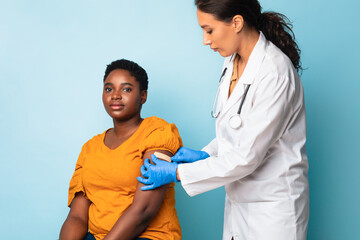 Doctor Applying Plaster Strip On Arm After Injection, Blue Background