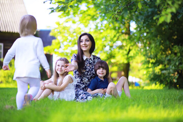 Obraz premium Young large family on a summer morning walk. Beautiful mother with children is playing in the park.