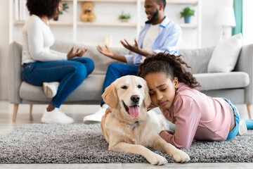 Sad black girl embracing dog, parents fighting in the background