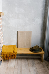 Brown plaid, felt hat and canvas on a wooden bench in the interior of a Scandinavian minimalist house
