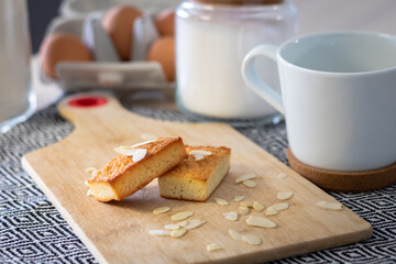 Gros plan sur des gâteaux financiers bien dorés sur une planche à découper parsemé d’amandes effilées
