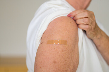 Anonymous lady showing the plaster covering her vaccination site