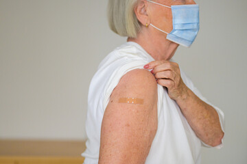 Anonymous lady showing the plaster covering her vaccination site